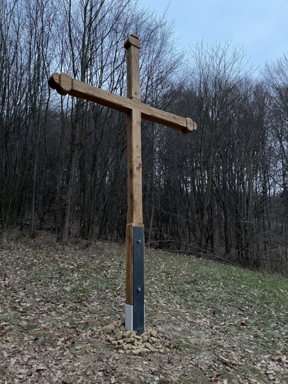 Tesaný kříž je osazený v areálu Janúšovy usedlosti